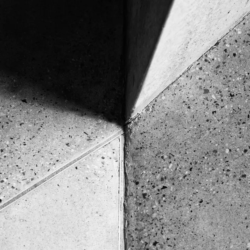 Encontro de planos de concreto e granilite sob luz rasante