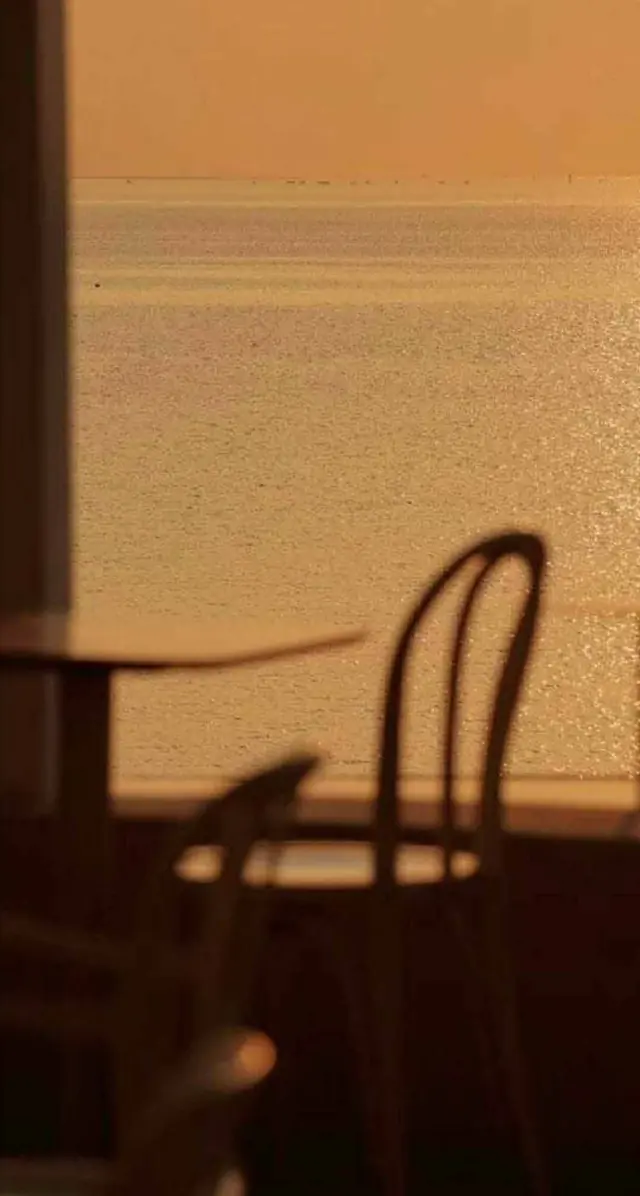 Sombra de uma cadeira projetada em parede à luz do fim de tarde
